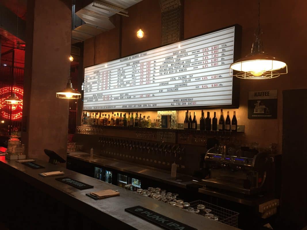 Eine Bar mit beleuchtetem Menüboard schafft eine stimmungsvolle Atmosphäre im warmen Licht.