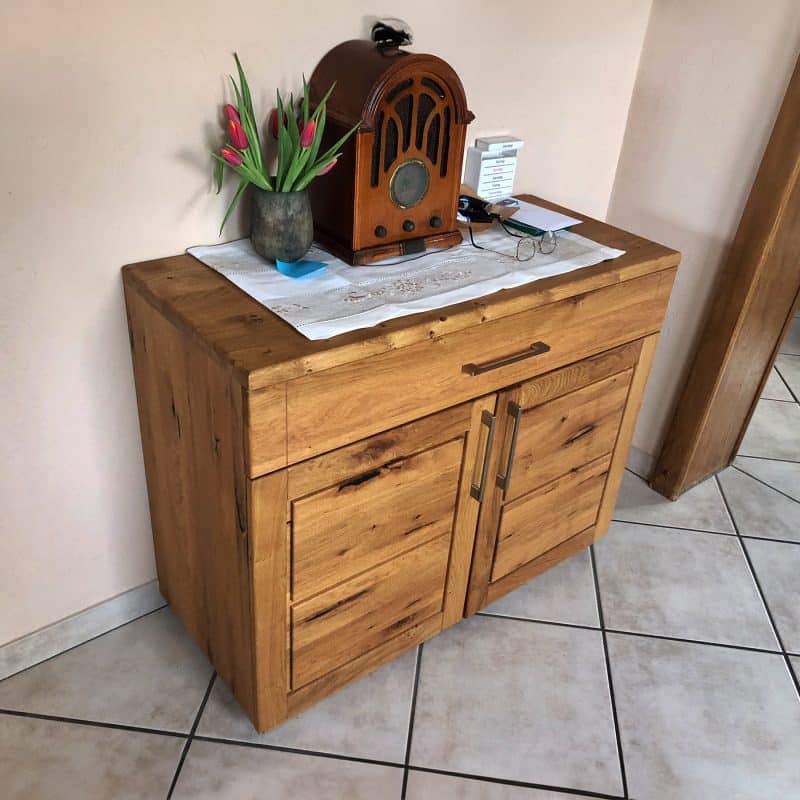 Ein kleiner Holzschrank steht in einem hellen Raum und zeigt Dekoration.