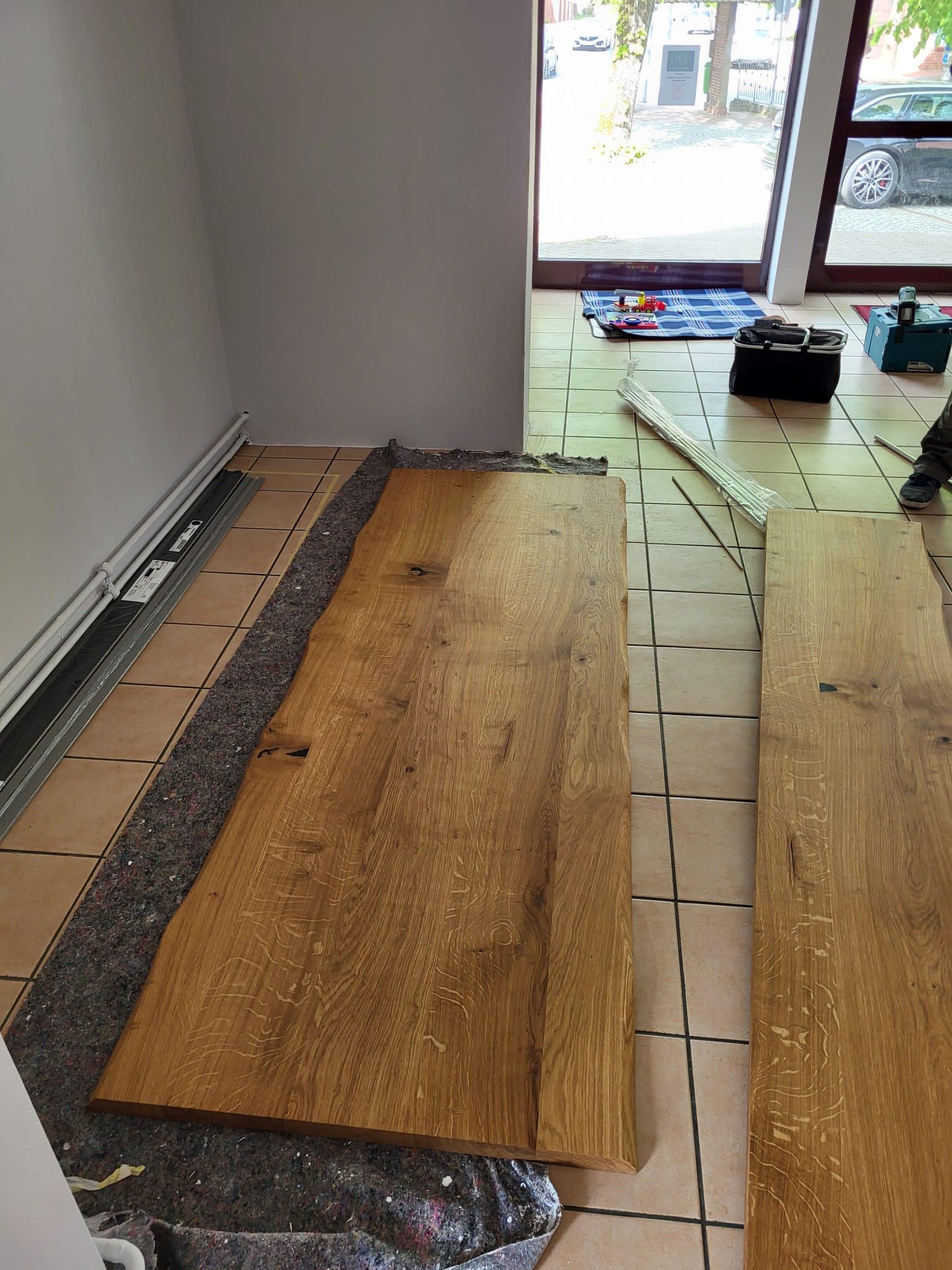 Große Holzbretter liegen auf dem Boden für weitere Verarbeitung bereit.
