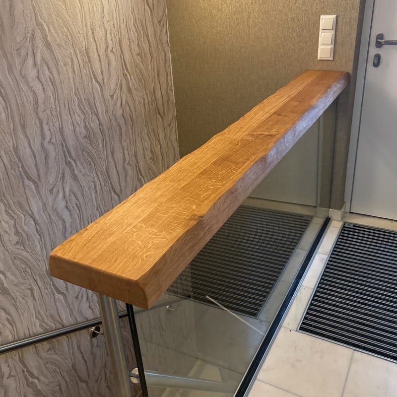 Ein Holzhandlauf verläuft sauber entlang einer hellen Treppenwand.
