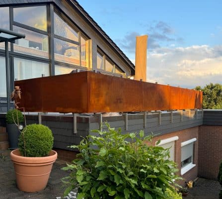 Das große Cortenstahl-Element bildet einen rostigen Sichtschutz auf der Terrasse.