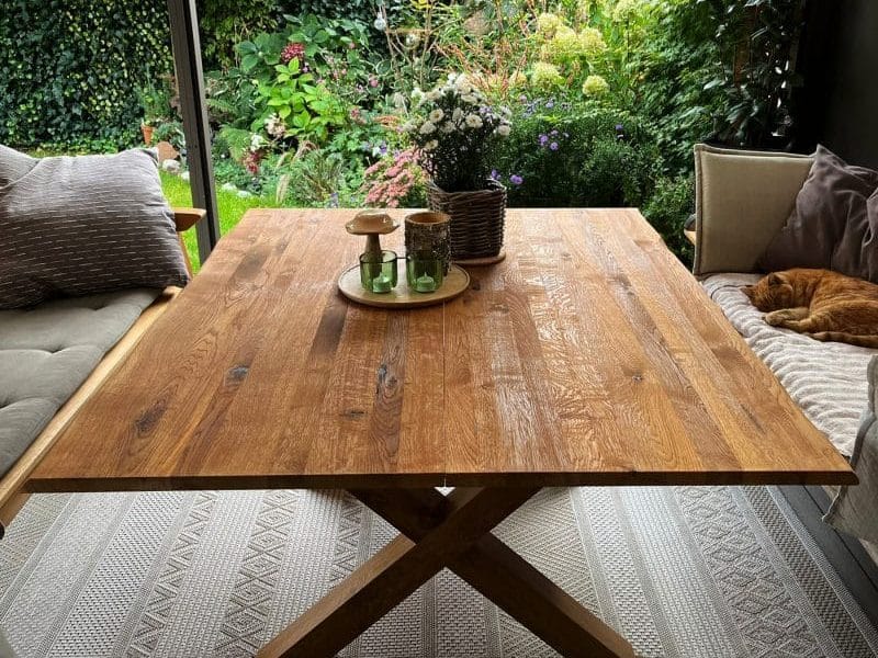 Massiver Eichenholztisch auf überdachter Terrasse im Grünen.
