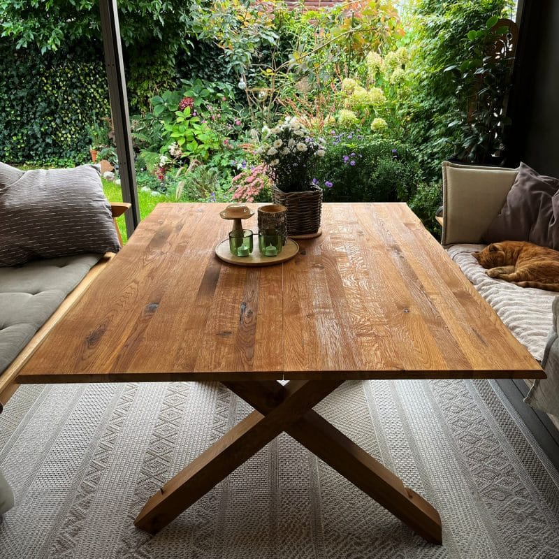 Ein massiver Esstisch aus Holz bringt Wärme und Natürlichkeit auf die Terrasse.