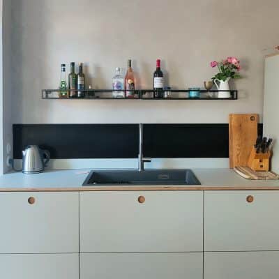 Schwarze Küchenrückwand aus gezundertem Schwarzblech hinter Herd und Spüle als moderner Spritzschutz montiert.