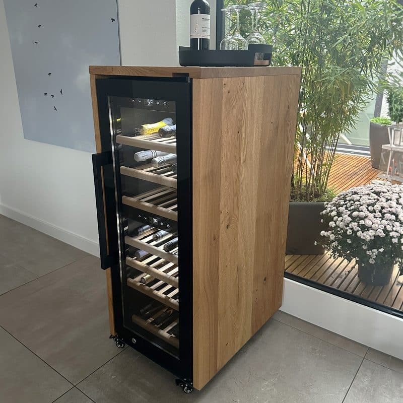Ein freistehender Wein-Kühlschrank ist mit einer Holzverkleidung in den Wohnraum integriert.