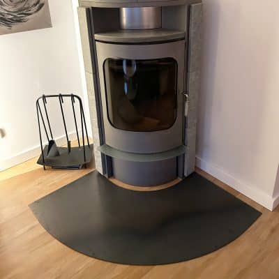 Moderner Kaminofen mit halbkreisförmiger Funkenschutzplatte.