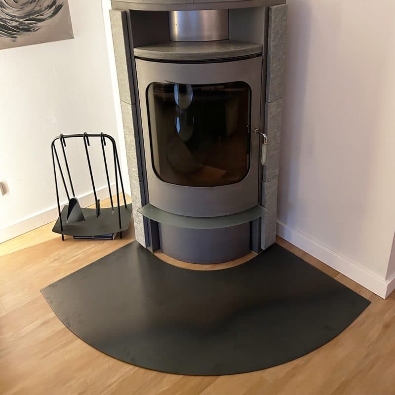 Moderner Kaminofen mit halbkreisförmiger Funkenschutzplatte.