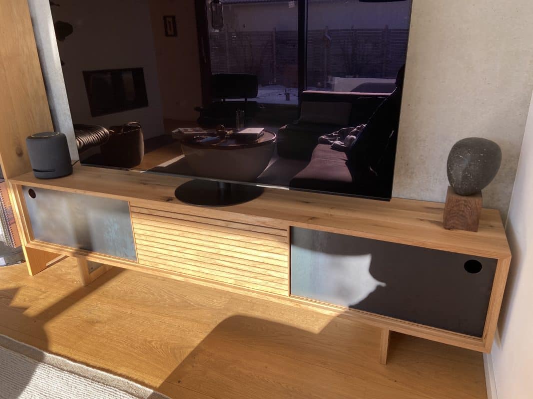 Ein Sideboard aus Holz zeigt dunkle Metallfronten im warmen Sonnenlicht.