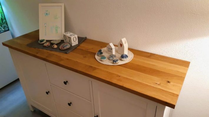 Massivholzplatte liegt auf einem weißen Sideboard.