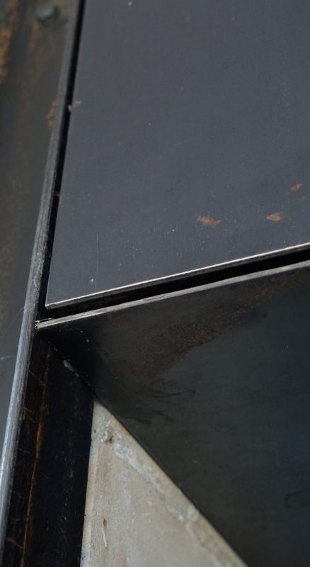 Detailaufnahme von Schwarzblech mit sichtbarer Kante und Rostspuren.