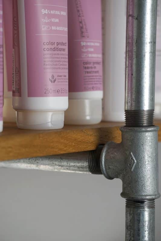 Haarpflegeprodukte auf einem Regal aus Holz und Stahlrohren.