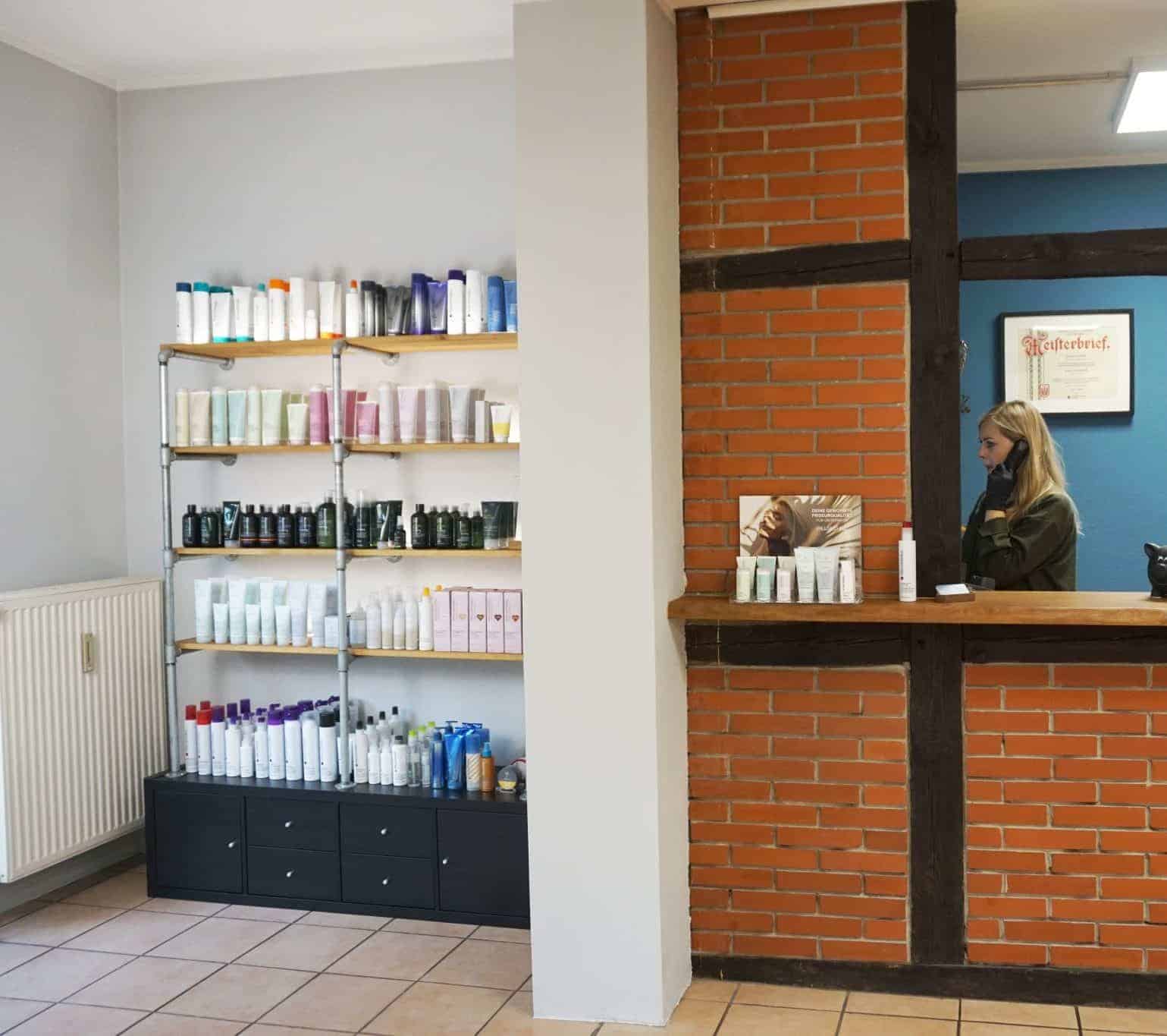 Ein Salon zeigt Regale voller Haarprodukte neben einem kleinen Empfangstresen.