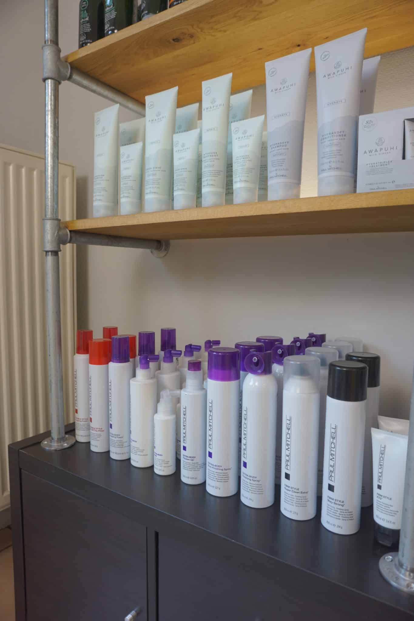 Diverse bunte Haarsprays und Shampoo-Flaschen stehen ordentlich in einem Regal.