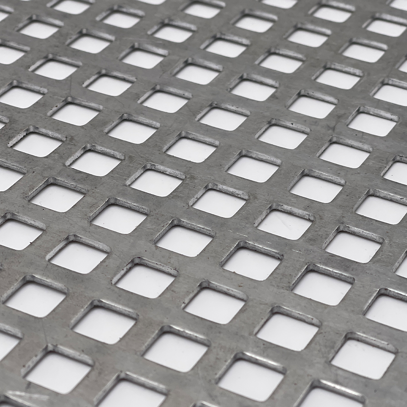 Nahaufnahme eines quadratisch gelochten Metallblechs mit regelmäßiger Struktur.
