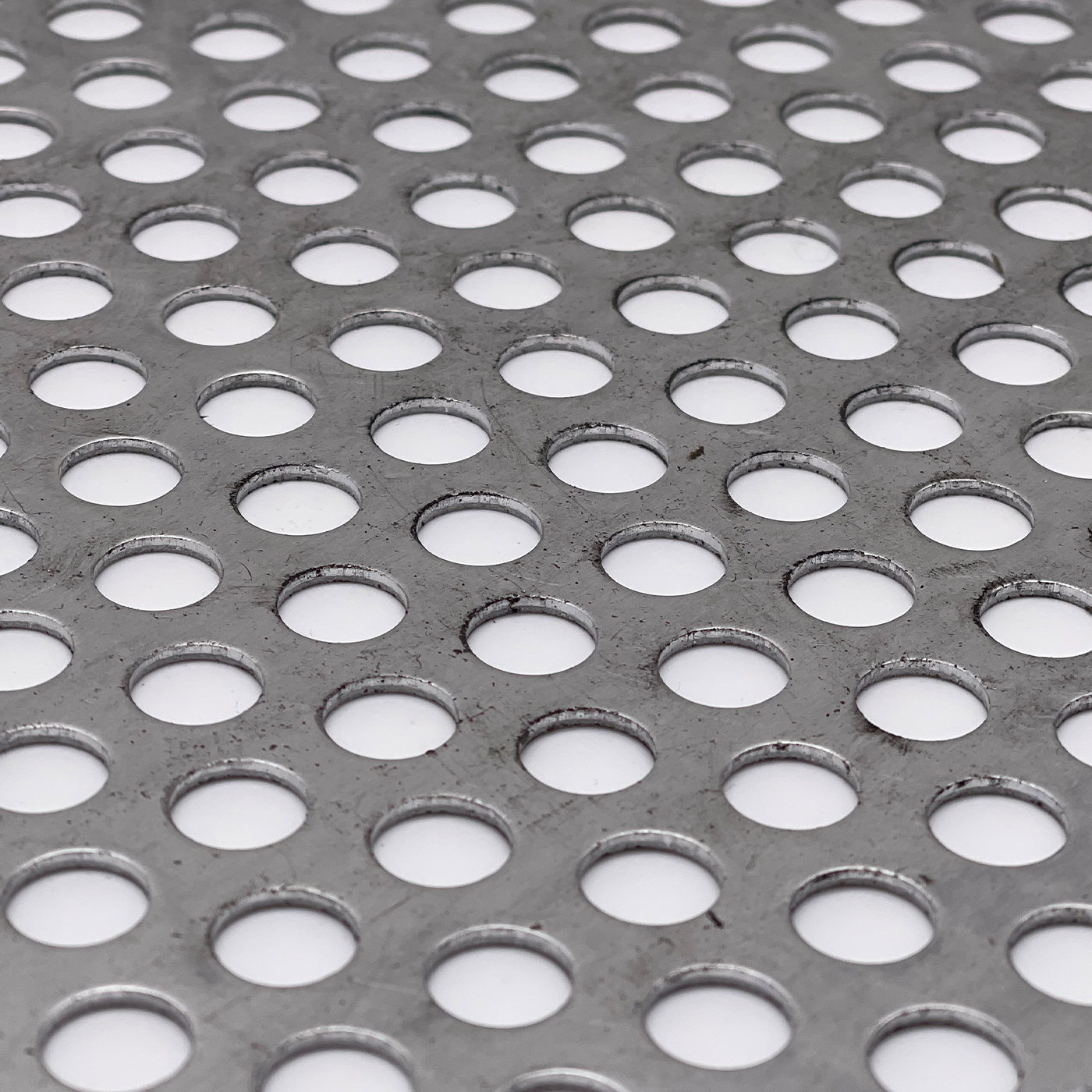 Nahaufnahme eines rund gelochten Metallblechs mit regelmäßiger Struktur.