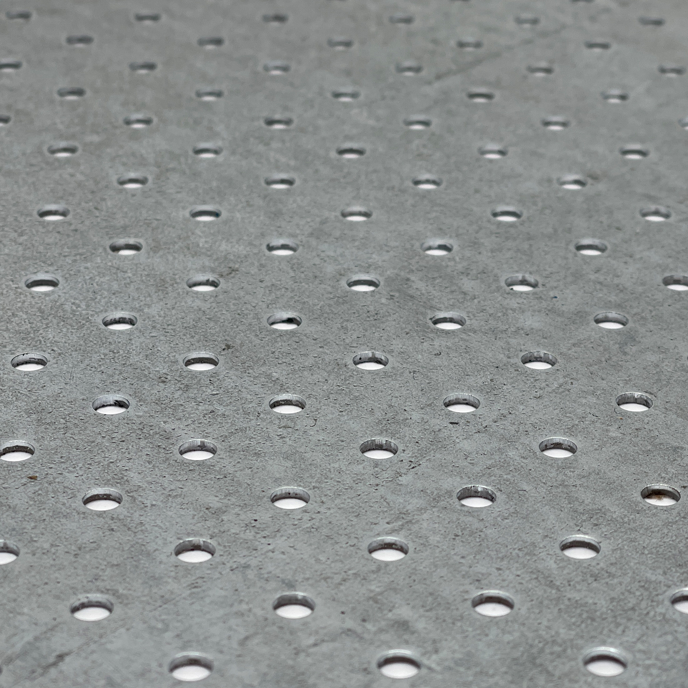 Nahaufnahme eines rund gelochten Metallblechs mit regelmäßiger Struktur.