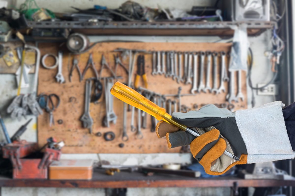 Kreuzschlitzschraubendreher in Werkstatt-Handschuh gehalten.