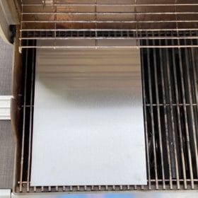 Detailaufnahme einer Edelstahl-Grillplatte auf einem Grillrost, gefertigt nach Maß.
