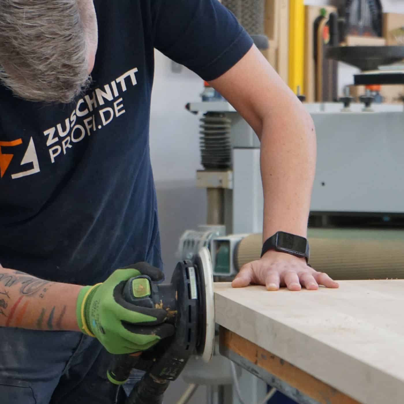 Eine Person schleift eine massive Holzplatte mit einer professionellen Handschleifmaschine.
