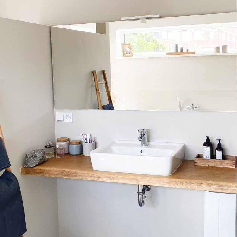 Ein heller Badezimmerbereich zeigt ein Waschbecken auf einer warmen Holzplatte.