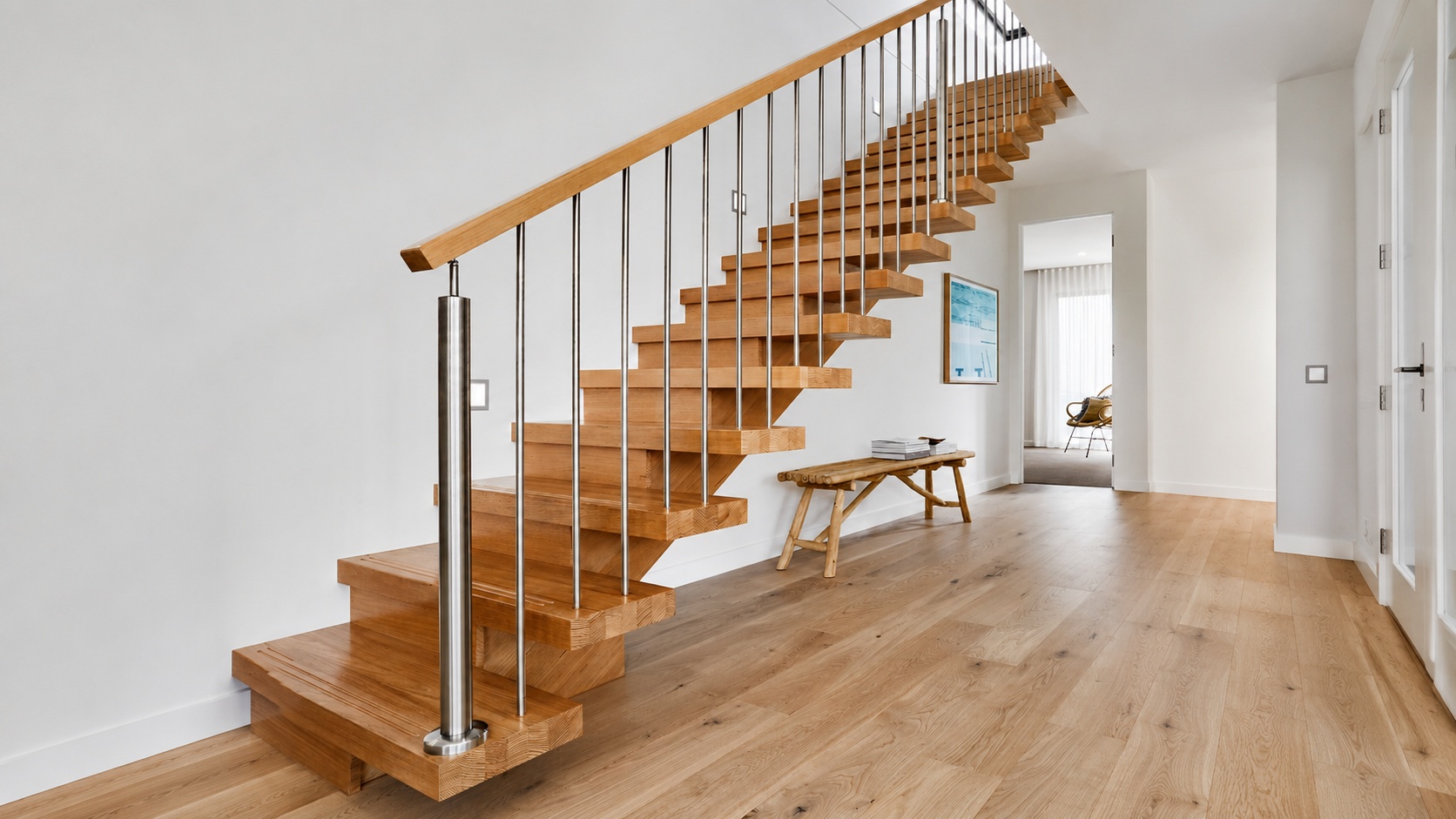 Eine Treppe mit Eichenstufen und Edelstahlgeländer steht in einem hellen Wohnflur.