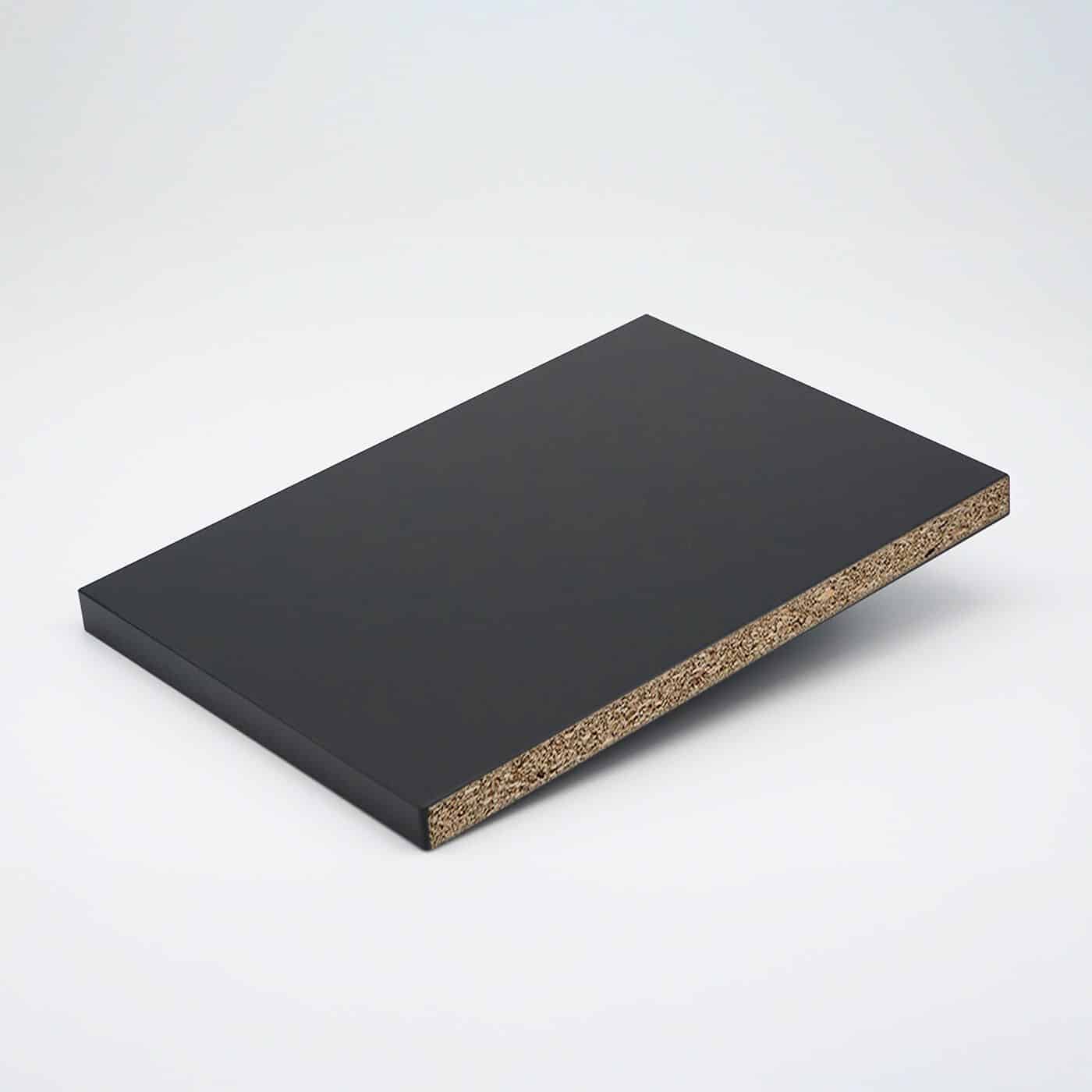 Schwarze Dekorplatte mit sichtbarer Spanplattenstruktur an der Kante.