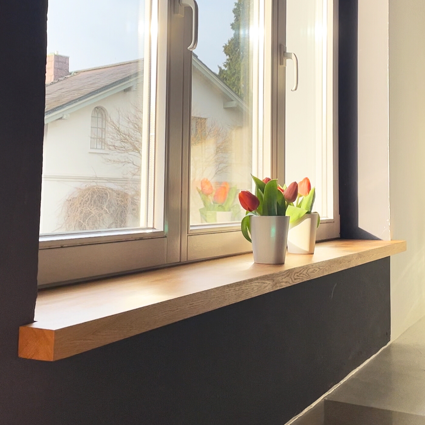 Fensterbank aus massiver Eiche, glatt geschliffen, mit natürlicher Maserung, montiert unter einem Fenster im Innenraum.