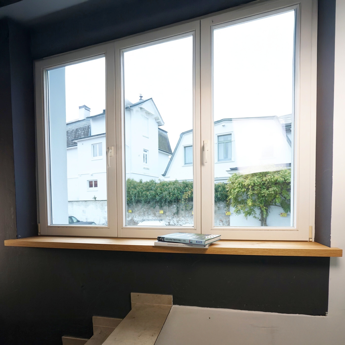 Helle Fensterbank aus Holz mit Büchern vor weißem Fenster.
