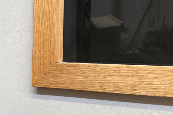 Eine Holzrahmenkante fasst eine Glasfläche sauber ein.