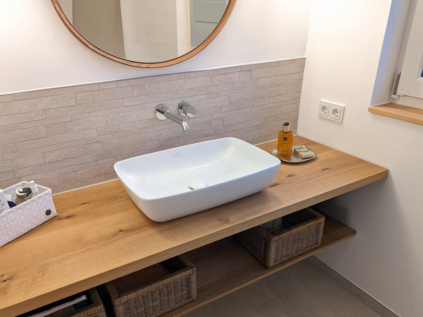 Ein moderner Waschtisch aus Holz mit einem Aufsatzwaschbecken steht in einem Badezimmer.