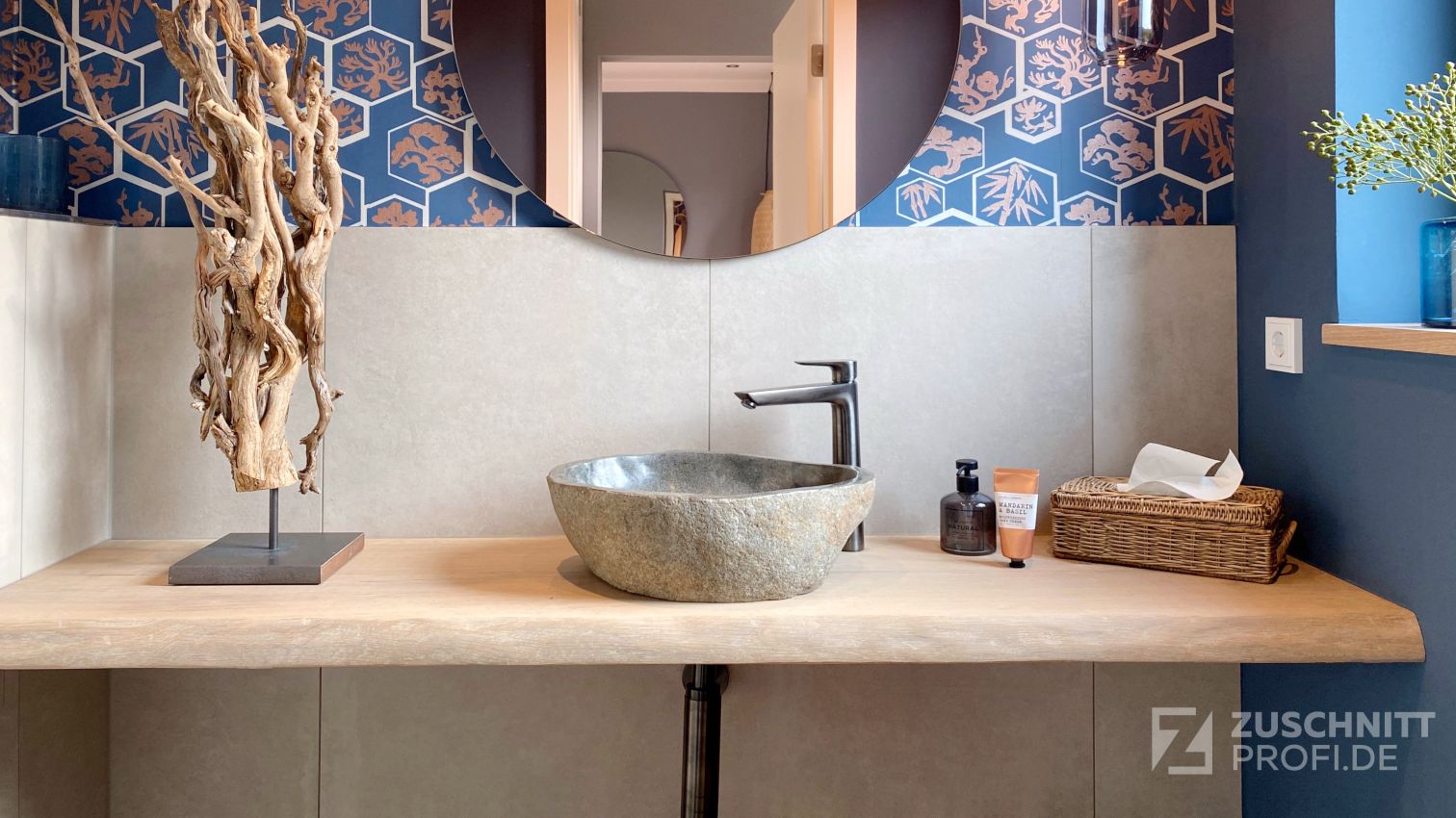 Modernes Badezimmer mit Holzwaschtisch, Steinwaschbecken, runder Spiegelwand und blauer Muster-Tapete.