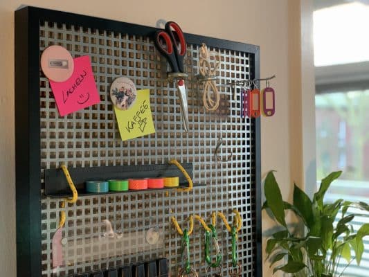 Eine Werkzeugwand mit Haken und bunten Notizen hängt im Arbeitsraum.