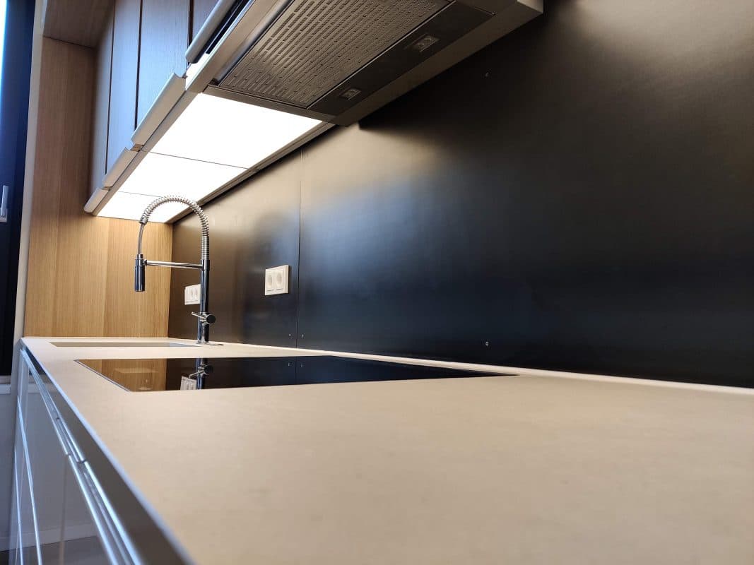 Die schwarze Rückwand einer modernen Küche zeigt eine ruhige, matte Oberfläche hinter Spüle und Arbeitsplatte.