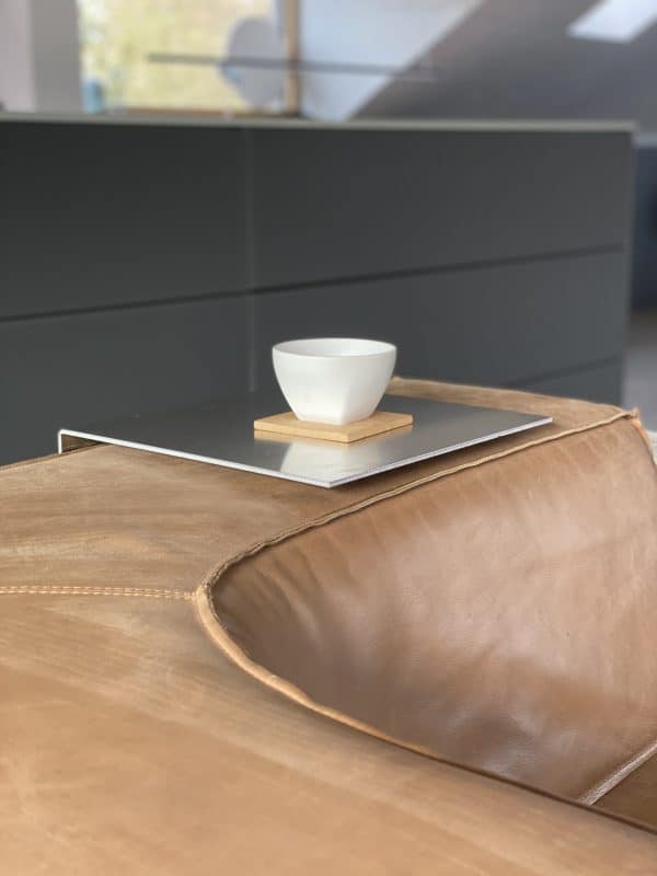 Weiße Schale auf Metallablage über brauner Ledercouch.