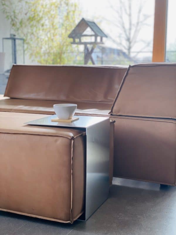 Braunes Ledersofa mit modernem Metall-Beistelltisch und Kaffeetasse.