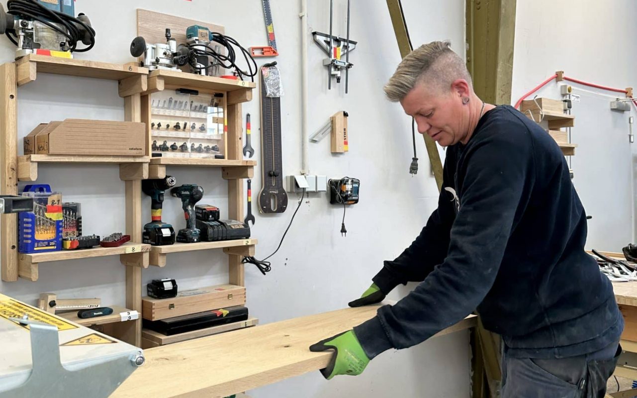 Werkstattarbeiterin fertigt ein Holzbrett in einer Werkstatt an.