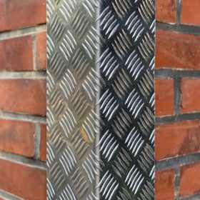 Aluminium-Riffelblech mit markanter Struktur setzt einen robusten Akzent an der Backsteinwand.