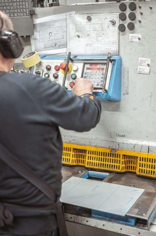 Ein Maschinenbediener stellt eine Einstellung an einem industriellen Steuerpult ein.
