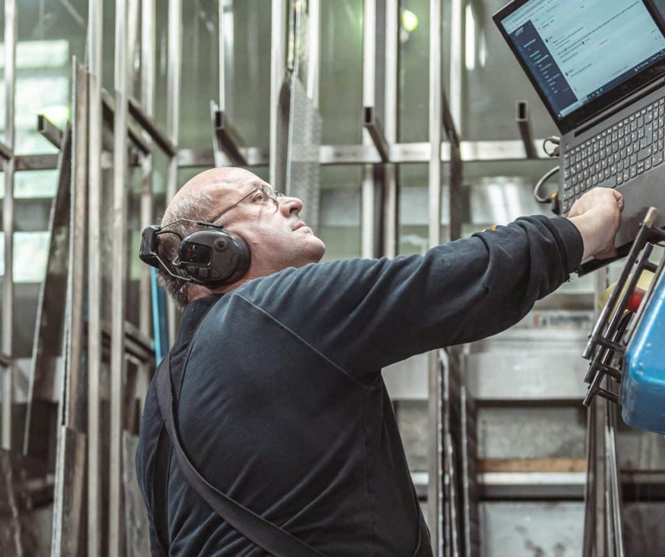 Ein Mitarbeiter arbeitet konzentriert an einer Metallmaschine in der Werkstatt.