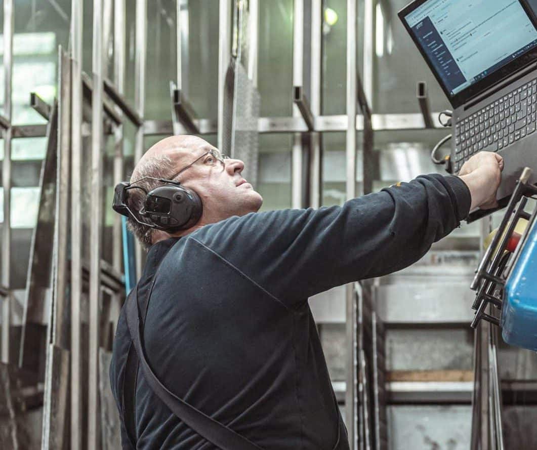 Ein Mitarbeiter arbeitet konzentriert an einer Metallmaschine in der Werkstatt.