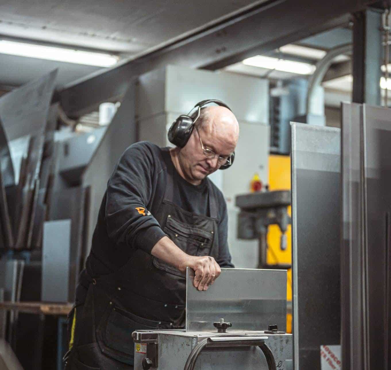 Ein Mitarbeiter von zuschnittprofi.mom bearbeitet ein Metallteil in der Produktionshalle.