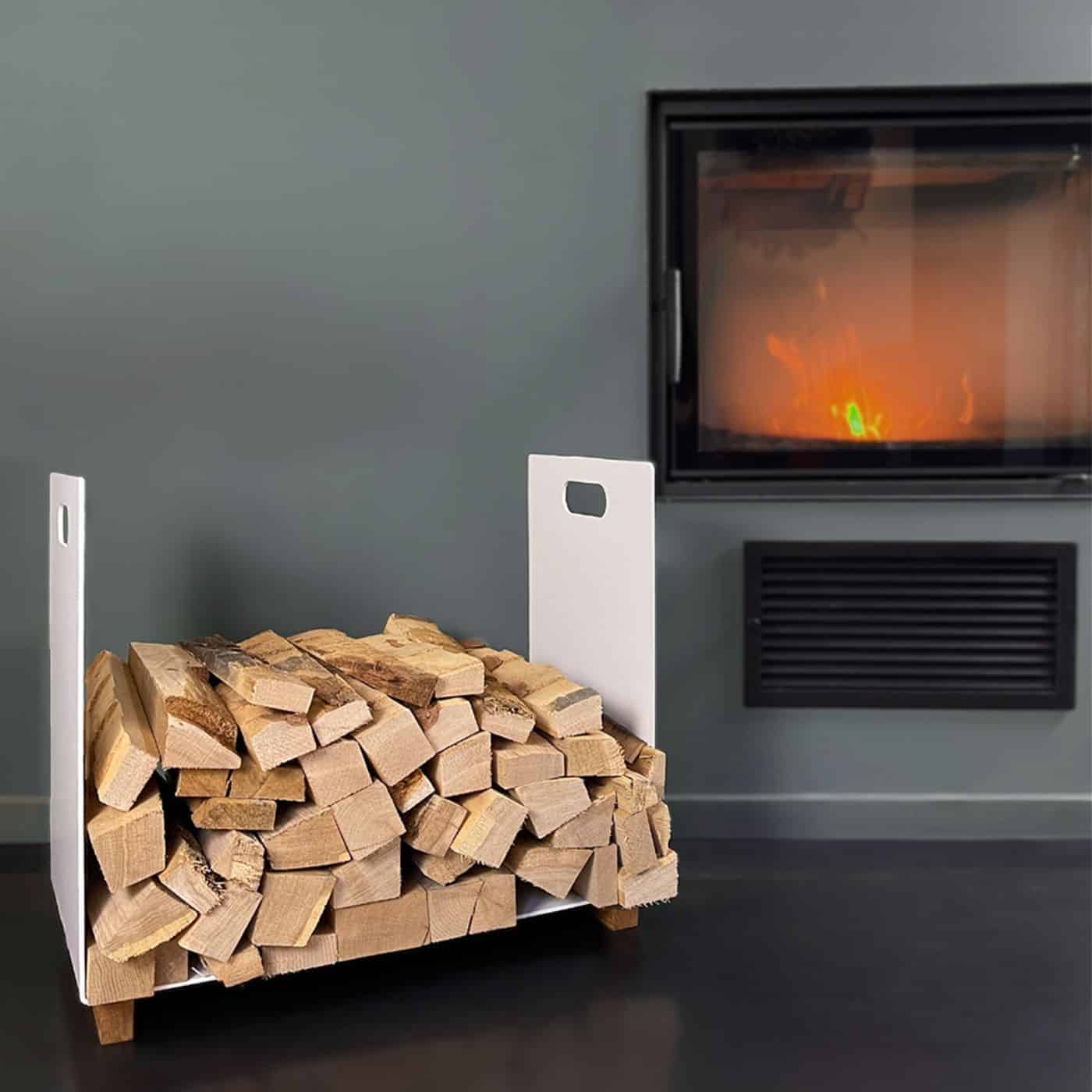 Ein schwarzer Holzkorb steht vor einem Kamin und ist mit Feuerholz gefüllt.