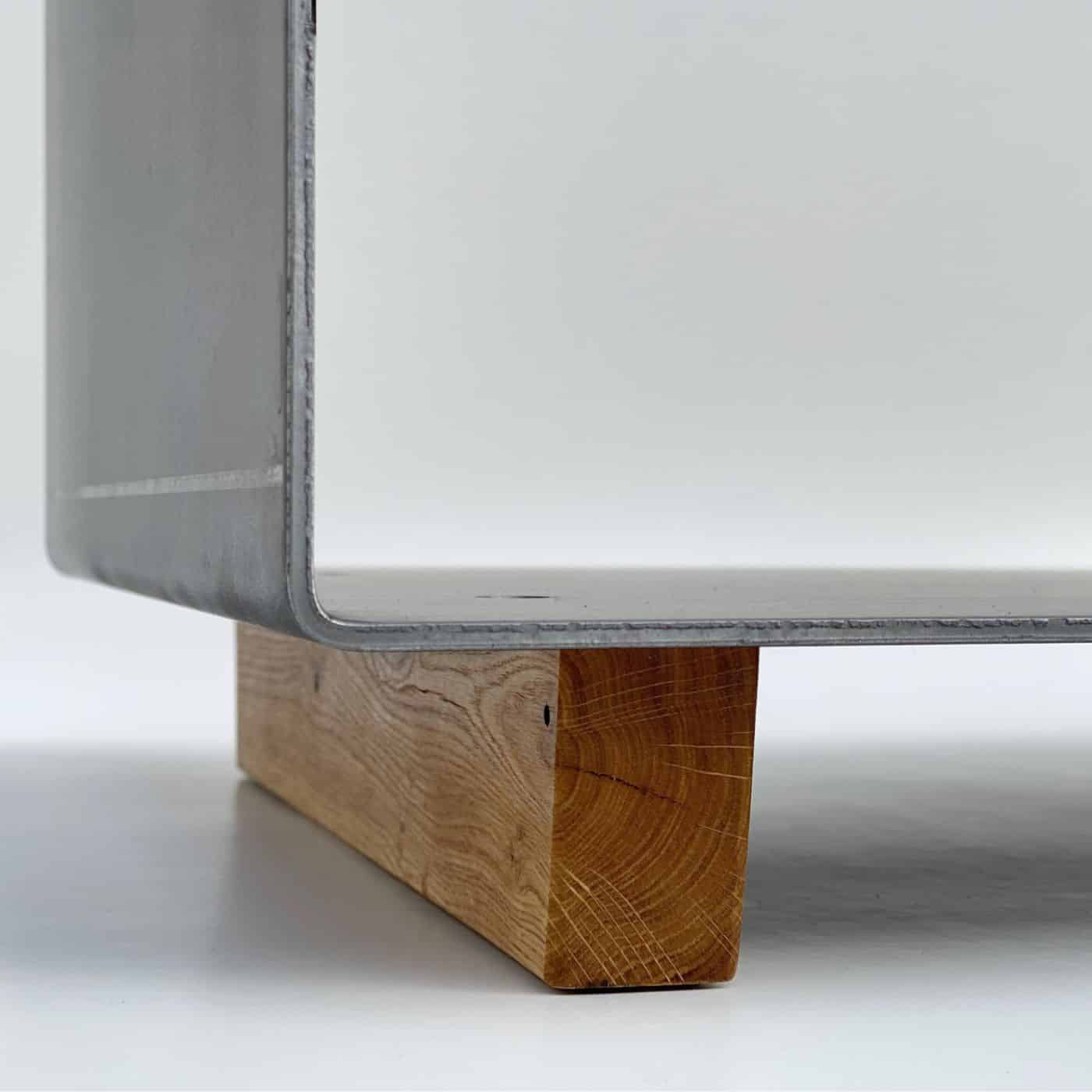 Metallschale der Kaminholzaufbewahrung auf einem massiven Eichenholzfuß, minimalistisch und robust.