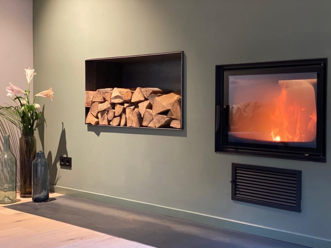 Moderner Wandkamin mit Feuer und Holzlagerung daneben.