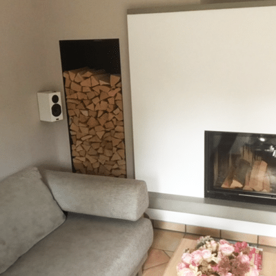 Ein Kamin mit Holzlager steht neben einer gepolsterten Sitzbank im Raum.