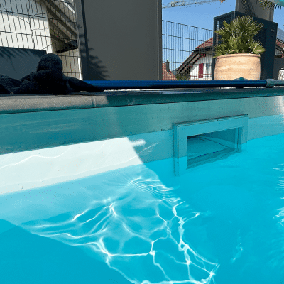 Eine Poolkante liegt direkt am klaren Wasser mit sichtbaren Lichtreflexionen.