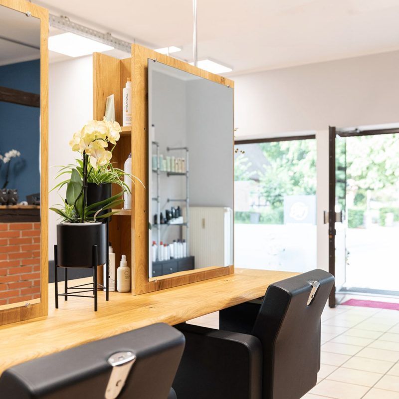 Ein Arbeitsbereich aus Holz prägt den Friseursalon und schafft eine offene, einladende Arbeitsatmosphäre.