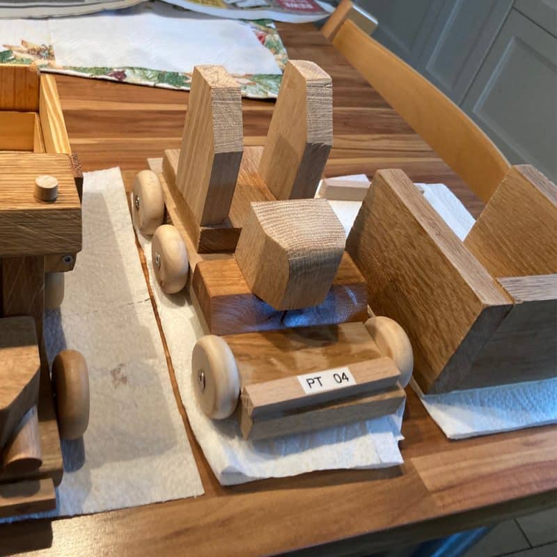 Liebevoll gebaute Holzfahrzeuge stehen fertig montiert und sorgfältig geschliffen auf dem Tisch.