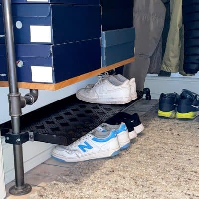 Eine schwarze Stahlablage aus Riffelblech hält Schuhe übersichtlich und platzsparend unter der Garderobe.