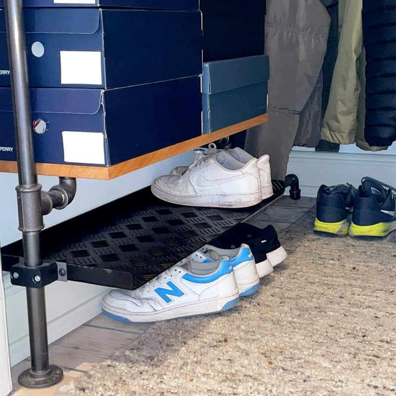 Eine schwarze Stahlablage aus Riffelblech hält Schuhe übersichtlich und platzsparend unter der Garderobe.